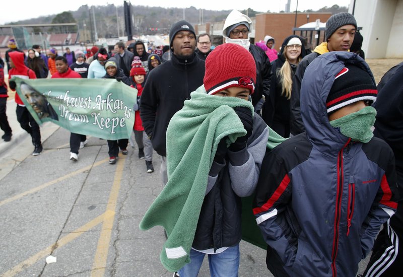 Jonathan Gadison (left), 13, shares a blanket with Caleb Henry, 14, as they participate Monday in the annual Martin Luther King Jr. Freedom March to the campus of the University of Arkansas in Fayetteville. Participants in the march, sponsored by the Northwest Arkansas Martin Luther King, Jr. Council, began near the corner of Razorback Road and Martin Luther King, Jr. Boulevard and marched, sang and chanted to the Arkansas Union for the Martin Luther King, Jr. Vigil co-sponsored by the University of Arkansas Associated Student Government and the Black Student Association. The keynote speaker was Yvette Murphy-Erby, vice provost for diversity and inclusion, at the university.