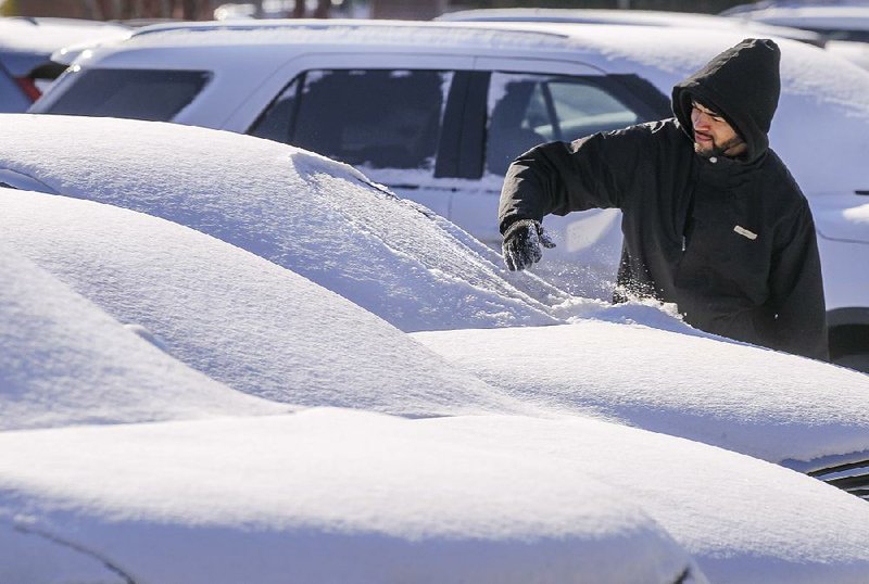 Arkansas Democrat-Gazette/BENJAMIN KRAIN --1/16/18--
Bailey Williams, a valet for the Little Rock Marriott, scrapes snow off the windshield of a vehicle left overnight in the hotel parking lot as he goes to retrieve it for a guest on Tuesday morning.