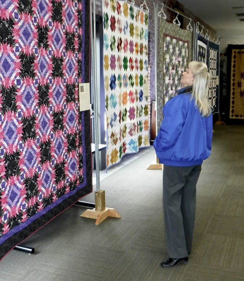 Westside Eagle Observer/RANDY MOLL Sandy Brandon looks at quilts on display at the Gentry Quilt Show, in the McKee Community Room of the Gentry Public Library on Monday. The quilt show continues until Friday afternoon, at about 2 p.m.