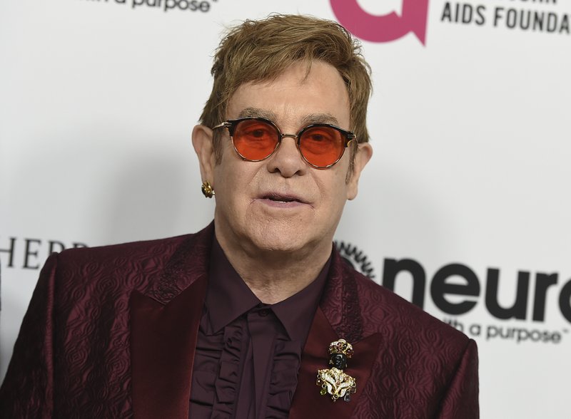 In this March 25, 2017 file photo, Elton John arrives at Elton John's 70th Birthday and 50-Year Songwriting Partnership with Bernie Taupin celebration in Los Angeles. Elton John is headed to the Grammys to help the organization celebrate its 60th awards show. The Recording Academy announced Wednesday, Jan., 17, 2018 that John and Irish rock band U2 will perform at the Jan. 28 show at Madison Square Garden in New York. 