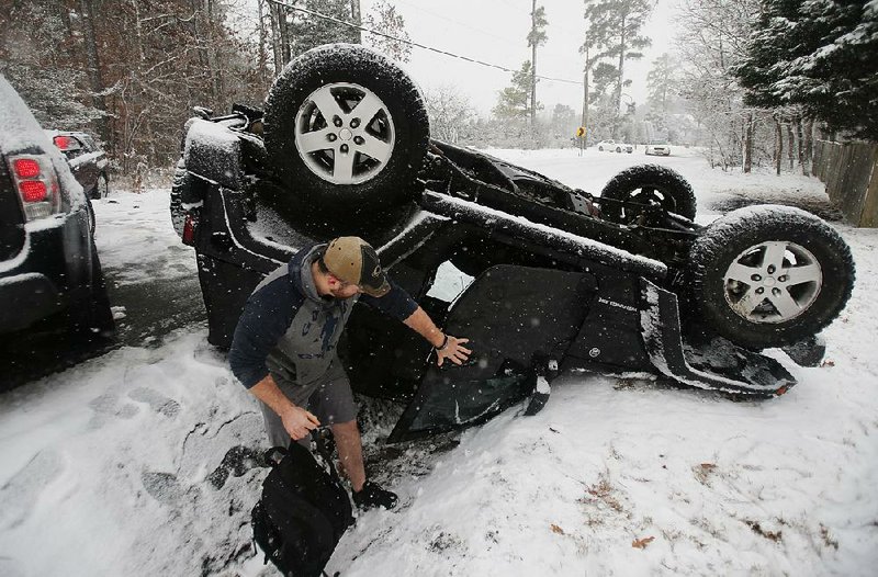 Julius Rigole, wearing shorts, gets belongings from his overturned Jeep after an accident Wednesday on a snow-covered road in Richmond, Va. The storm that delivered treacherous road conditions and dangerously low temperatures to Arkansas earlier in the week is spreading a record-breaking blast of cold across the South and eastward. Little Rock recorded a low of 7 degrees early Wednesday, the National Weather Service said.  
