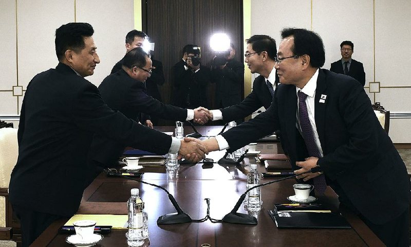 North Korean officials (left) shake hands with South Korean Unification Ministry officials Wednesday in the border village of Panmunjom after reaching agreement to field a unified Olympic team with their athletes parading together when the games open next month at Pyeongchang, South Korea. 