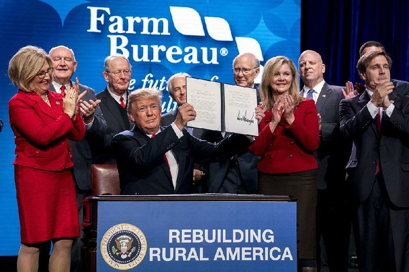 President Donald Trump holds up a signed executive order and a memorandum on rural broadband access at the American Farm Bureau Federation’s annual convention Jan. 8 in Nashville, Tenn. 