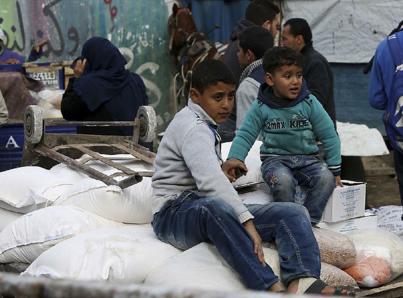 Refugees sit atop sacks of flour Wednesday at a U.N. food distribution center in the Gaza Strip.