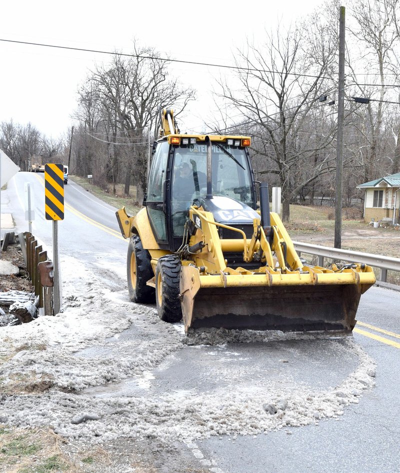 Westside Eagle Observer/MIKE ECKELS Decatur street department crews used a backhoe to scrape ice off of the Branch Creek bridge on South Main Street in Decatur Jan. 2. A broken waterline on Buckner Avenue leaked water on the bridge which froze almost immediately due to subfreezing temperatures.