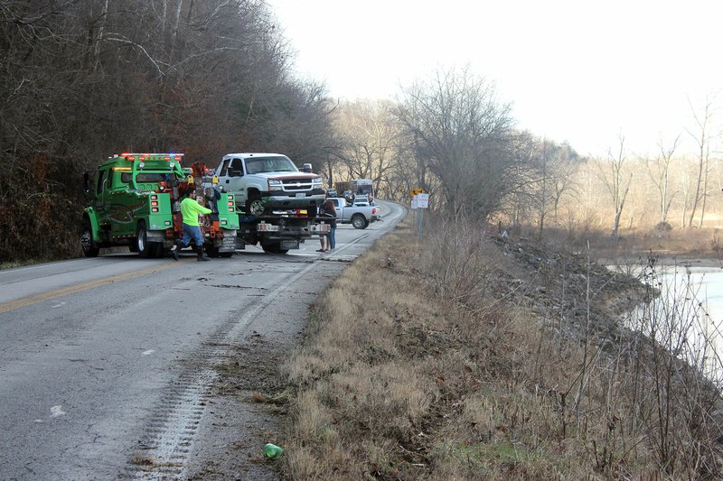 MEGAN DAVIS/MCDONALD COUNTY PRESS Employees from Ron's Towing Service labored to remove a Chevrolet pickup from the Elk River shortly after 11 a.m. on Wednesday, Jan. 10. Reports from the Missouri Highway Patrol indicate the vehicle left Route H, between Pineville and Noel, and overturned into the waterway close to five hours earlier.