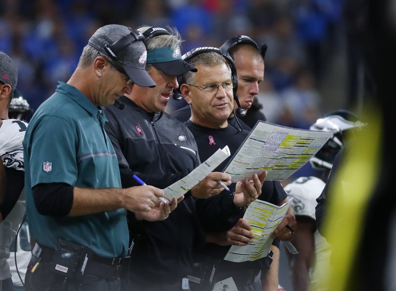 FILE - In this Oct. 9, 2016, file photo, from left, Philadelphia Eagles offensive coordinator, Frank Reich, head coach Doug Pederson, offensive line coach Jeff Stoutland and tight ends coach Justin Peelle talk during an NFL football game against the Detroit Lions in Detroit. Whether it's a deep pass into the wind on the first play from scrimmage, going for it on fourth down or trying new plays, the Eagles' offensive coaching staff is aggressive no matter the conditions. (AP Photo/Paul Sancya, File)