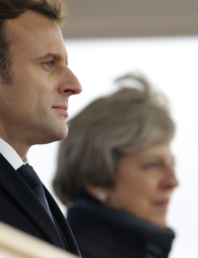 French President Emmanuel Macron and Britain's Prime Minister Theresa May listen to the national anthems as they arrive for an Anglo-French summit at the Royal Military College at Sandhurst, Camberley, England, Thursday, Jan. 18, 2018. 