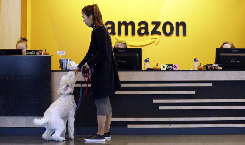 FILE - In this Wednesday, Oct. 11, 2017, file photo, an Amazon employee gives her dog a biscuit as the pair head into a company building, where dogs are welcome, in Seattle. Amazon announced Thursday, Jan. 18, 2018, that it has narrowed its hunt for a second headquarters to 20 locations, concentrated among cities in the U.S. East and Midwest. Toronto made the list as well, keeping the company's international options open. (AP Photo/Elaine Thompson, File)