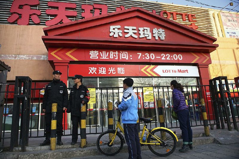 In March, Chinese security officials stand outside a Lotte supermarket that was closed under orders from Beijing’s Fire department after the South Korean retailer ran afoul of the government.