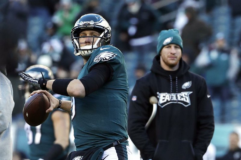 Philadelphia’s Nick Foles (left) warms up as Carson Wentz looks on before the Eagles’ divisional playoff game Sunday against Atlanta. Wentz is among a long list of top players sitting out the playoffs this year because of injuries. 