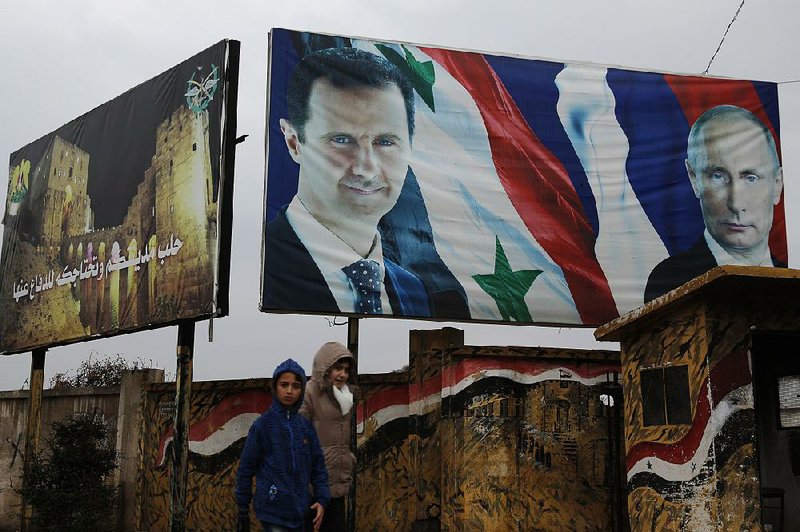 Syrians walk Thursday past billboards of Syrian President Bashar Assad (left) and Russian President Vladimir Putin in Aleppo as tensions rise between Syria and Turkey.