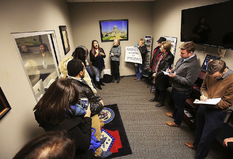Diana Pacheco (top, left) speaks out Thursday in U.S. Sen. Tom Cotton’s Little Rock office as other demonstrators line a wall and Cotton staff members take notes.