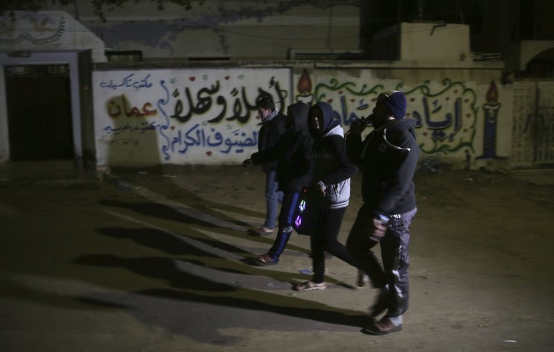 In this Wednesday, Jan. 3, 2018 photo, Palestinian volunteers walk with loudspeakers calling people to wake up for the dawn prayer, in Gaza City. In recent weeks, Gaza residents have been jolted awake in the dead of night to a raucous mixture of Quranic phrases, Islamic supplications and prayers delivered to their doorsteps. 