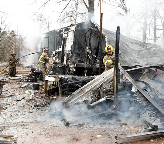 The Sentinel Record/Richard Rasmussen TRAILER ENGULFED: Members of the Lonsdale and Morning Star fire departments extinguish a trailer house fire at 354 Rigsby Loop on Friday. Eight firefighters from each department responded to the fully engulfed fire around 9 a.m. and had the flames controlled in less than 15 minutes. The probable cause was attributed to a wood stove fire which resulted in the total loss of the structure and belongings.