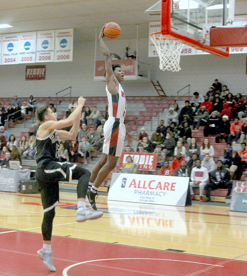 The Sentinel-Record/James Leigh HIGH-FLYING: Henderson State senior Kaylon Tappin flies to the hoop for two as Harding's Brandon Reeves defends at the Duke Wells Center in Arkadelphia Thursday night. The Reddies overcame a 12-point deficit in the first half and held on to win, 85-81.