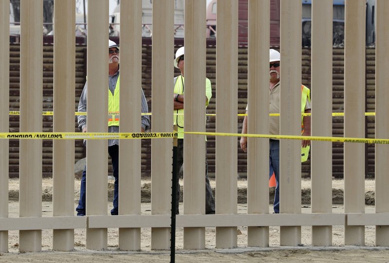 FILE - In this Oct. 19, 2017 file photo, crews work on a border wall prototype near the border with Tijuana, Mexico, in San Diego. A U.S. official says recent testing of prototypes of President Donald Trump's proposed wall with Mexico found their heights should stop border crossers. U.S. tactical teams spent three weeks trying to breach and scale the models in San Diego. An official with direct knowledge of the results said they point to see-through steel barriers topped by concrete as the best design. The official spoke to The Associated Press on condition of anonymity because the information is not authorized for release. (AP Photo/Gregory Bull, File)