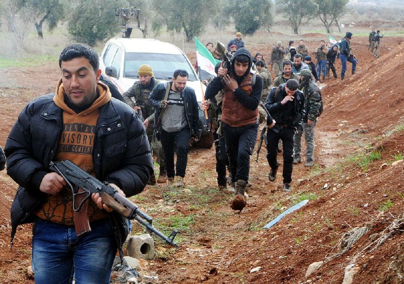 Turkey-backed Free Syrian Army fi ghters carry weapons Friday in the Syrian town of Azaz, near the border with Turkey.