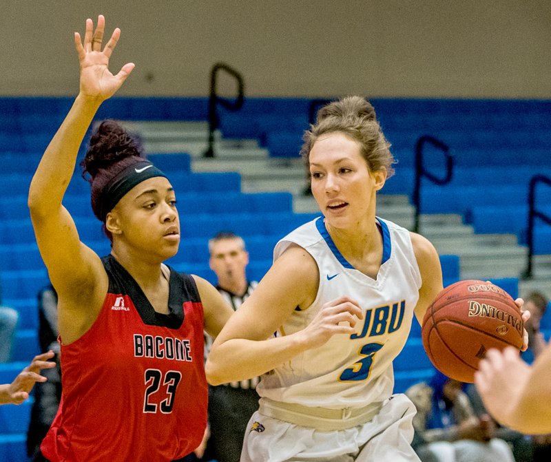 Photo courtesy of JBU Sports Information John Brown University senior Jana Schammel dribbles the ball as Bacone's Juanita Dodson defends on the play in JBU's 84-80 victory on Tuesday at Bill George Arena.