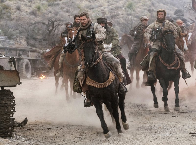 This image released by Warner Bros. Entertainment shows Chris Hemsworth, center, in a scene from "12 Strong". (David James/Warner Bros. Entertainment via AP)