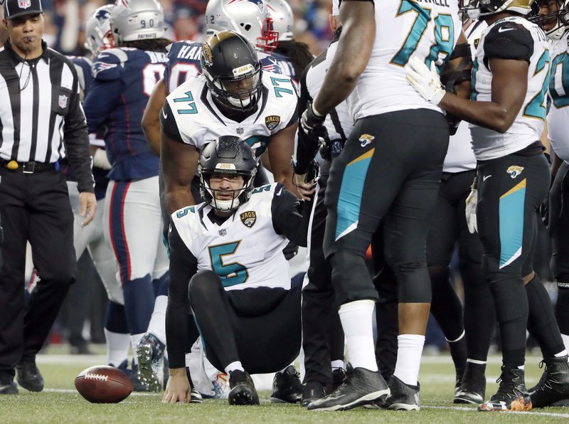 Jacksonville Jaguars guard Patrick Omameh (77) helps quarterback Blake Bortles (5) get up during the second half of the AFC championship NFL football game against the New England Patriots, Sunday, Jan. 21, 2018, in Foxborough, Mass. (AP Photo/Winslow Townson)