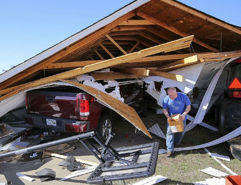 Zac Farley salvages valuables from his garage Monday after a tornado destroyed the structure at his home on Needs Creek Drive in Springhill.