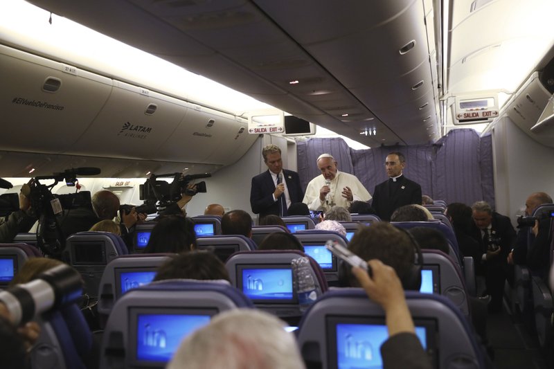 Pope Francis, flanked by father Mauricio Rueda, delegate for the organization of the papal journeys, right, and Greg Burke, spokesman of the Vatican, talks with journalists during his flight from Lima, Peru, to Rome, Sunday, Jan. 21, 2018. (AP Photo/Alessandra Tarantino)