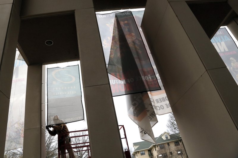 FILE — Patrick Ellis, an employee of the the Arkansas Arts Center in Little Rock, braves cold temperatures to secure a banner in front of the facility in this January 19, 2016 file photo.