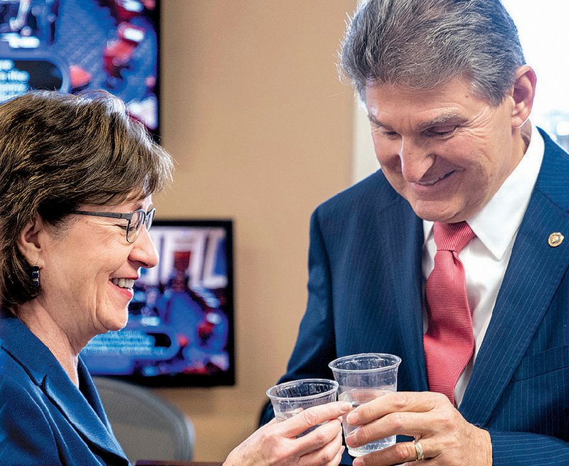 Sens. Susan Collins, R-Maine, and Joe Manchin, D-W.Va., toast each other as they wait to speak at a news conference on Capitol Hill on Monday in Washington after senators reached an agreement to advance a bill ending the government shutdown.