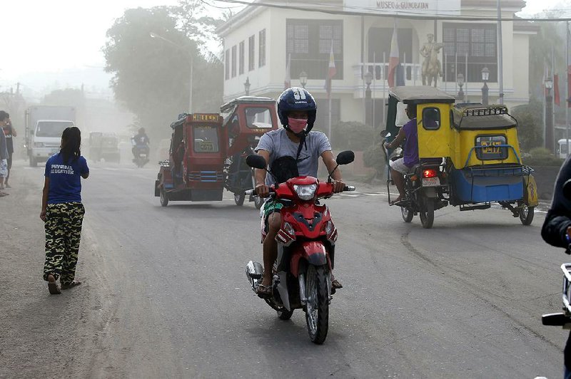 A motorcyclist wears a protective mask Wednesday as he rides through volcanic ash in the air and on the street in Guinobatan township southeast of Manila, Philippines. 