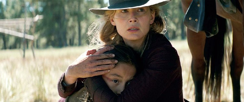 Widow Rosalie Quaid (Rosamund Pike) comforts Little Bear (Xavier Horsechief) in Scott Cooper’s traditionalist but violent Western Hostiles.
