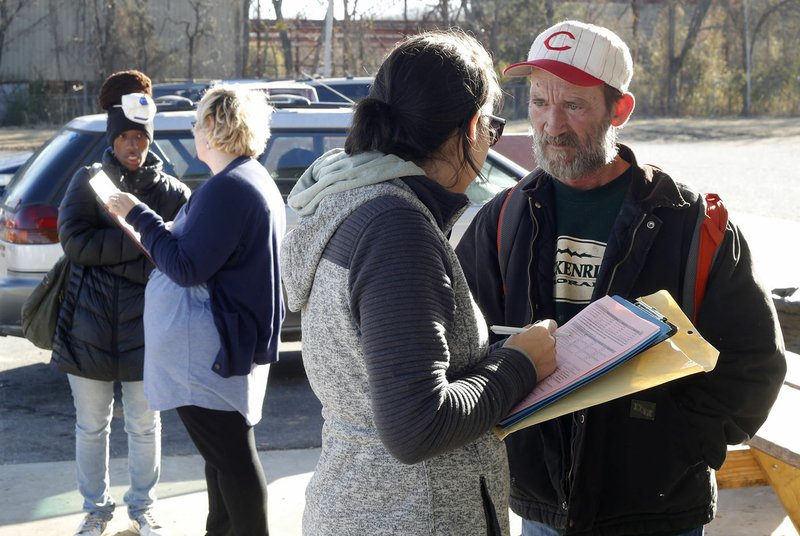 Jessica Andrews (left), CEO of 7 Hills Homeless Center, speaks Thursday with Jimmy Morgan (right), homeless, as she fills out a survey at the 7 Hills Day Center in Fayetteville. The Northwest Arkansas Continuum of Care held a 24-hour survey to gauge the scale of homelessness in the area. It’s the first time the survey has been done yearly instead of biannually.