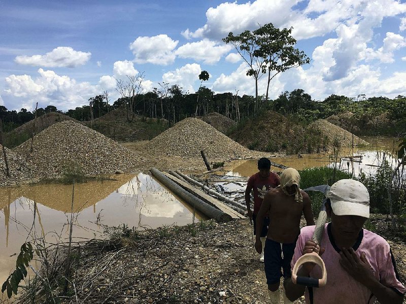 Illegal gold miners walk in a mining camp in Boca Colorado, part of Peru’s Madre de Dios province in the Amazon. It’s this forlorn corner of the Amazon that Pope Francis visited Jan. 19 amid what has been called a modern-day gold rush of illegal miners threatening the world’s largest rain forest. 