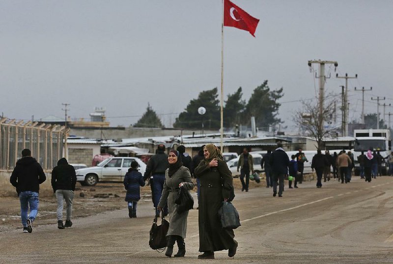 Syrians walk Friday in Turkey at the Oncupinar border crossing with Syria. Kurdish forces said Friday that Turkey’s incursion at the Syria border at Afrin in the north has left more than 100 civilians and fighters dead.  