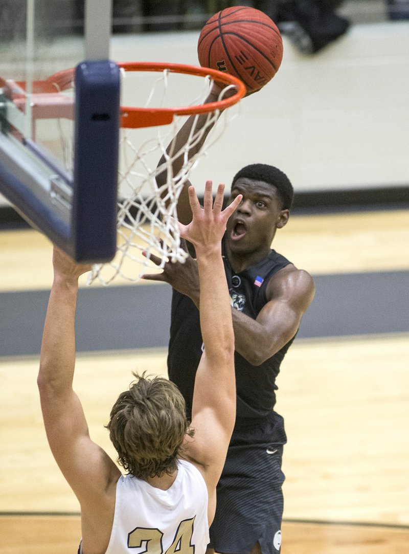 Bentonville High’s Cadarius Baggett (top) shoots over Bentonville West’s Ben Larsen on Friday at Bentonville West in Centerton.