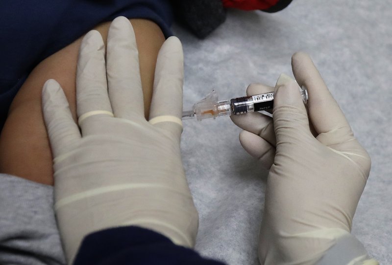 FILE - In this Jan. 12, 2018, file photo, Ana Martinez, a medical assistant at the Sea Mar Community Health Center, gives a patient a flu shot in Seattle. Flu season continues to get worse. In Arkansas, more than 120 people have died from the flu, setting the state record with the end of flu season still weeks away. (AP Photo/Ted S. Warren, File)