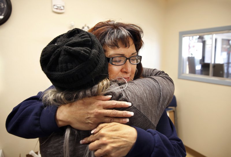 In this Thursday, Dec. 21, 2017 photo Joleen Valencia, who was held past her scheduled parole date while serving a drug-trafficking sentence, embraces social worker Sheila Ciminera at The Pavilions, a residential re-entry program in Los Lunas, N.M. New Mexico prison records show the state has held hundreds of inmates, like Valencia, past their projected parole dates under a practice widely known as “in-house parole.” (AP Photo/Eric Draper)