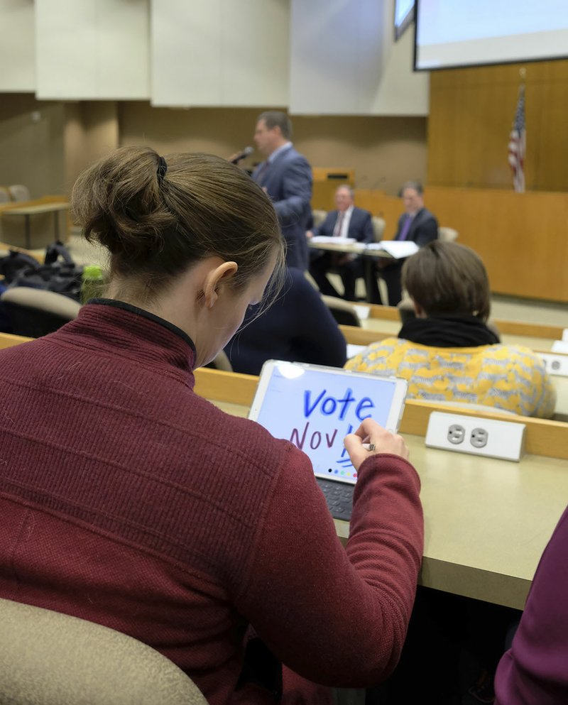 Kathleen Lehman, a University of Arkansas faculty member at Mullins Library, doodles as UA spokesman Mark Rushing and others answer questions Thursday about implementation of a new law allowing licensed individuals to carry guns on campus legally. Her doodle said "Vote Nov '18."