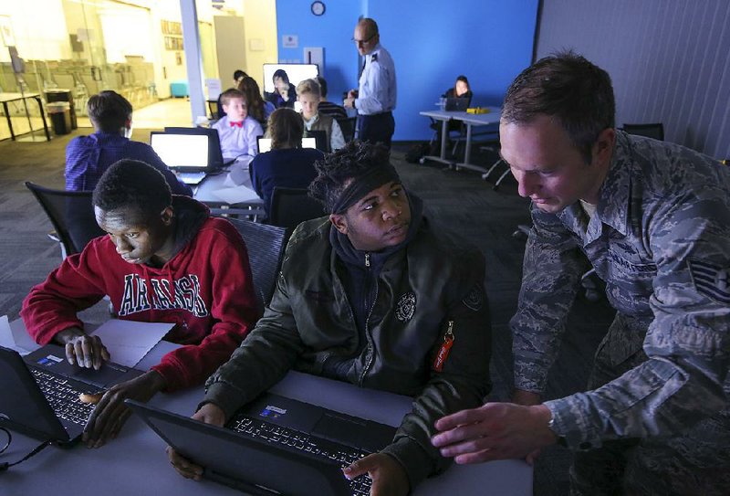 Jonathan Berg (right), an Arkansas Air National Guard cyberspace squadron instructor, helps Darius Wilson (left) and Christian Oliver, both from Mills High School, manipulate a Web application Monday during a training session in Little Rock.