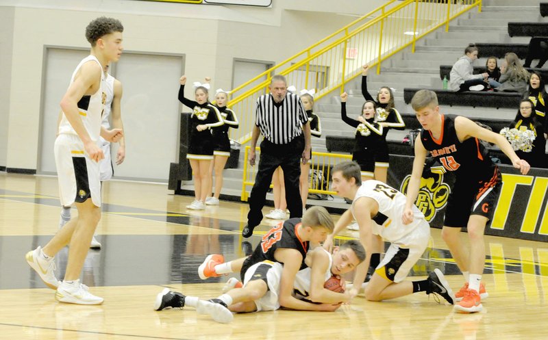 MARK HUMPHREY ENTERPRISE-LEADER/Prairie Grove junior Riley Rhodes protects the basketball from the efforts of Gravette sophomore Brayden Trembly to force a jump-ball. Prairie Grove junior Nick Pohlman and Brayden's older brother, Kelton Trembly, a Gravette senior, are also mixed up in the fray as Prairie Grove senior D.J. Pearson looks to help. Gravette squeaked by the Tigers, 59-57, on Jan. 23.