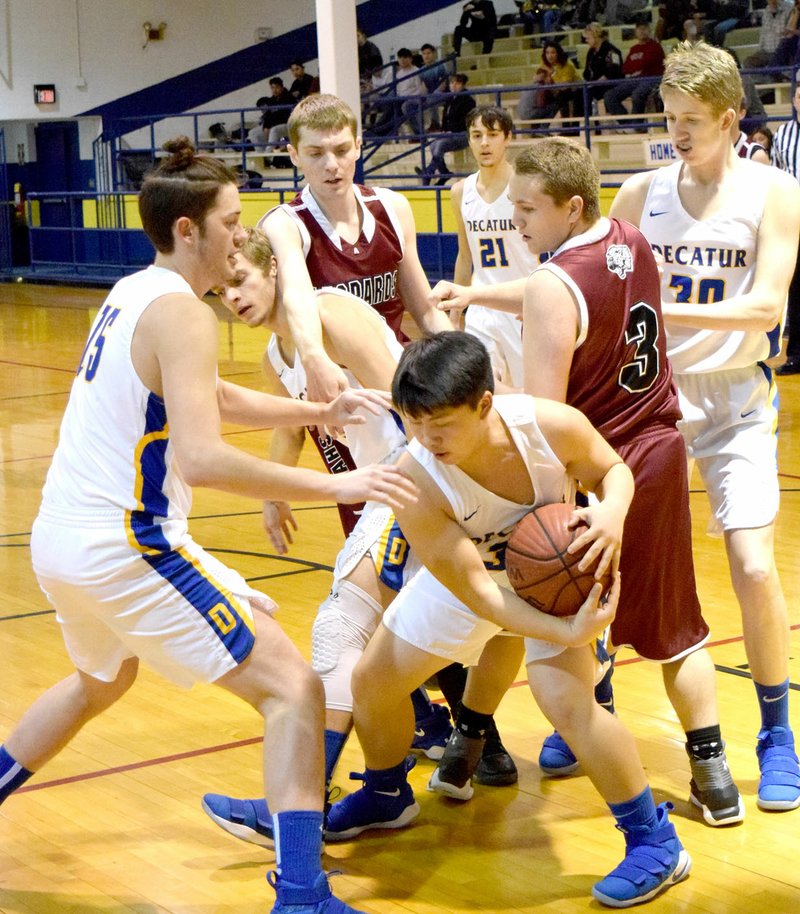 Westside Eagle Observer/MIKE ECKELS Decatur's Alex Lee (center) protects his rebound from two Leopard players during the second quarter of the Bulldogs-Leopards conference basketball contest at Peterson Gym in Decatur Jan. 23. The Leopards took the win, 49-28.