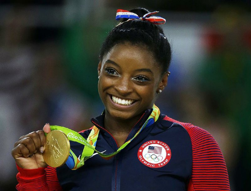 In this Aug. 16, 2016 file photo, United States gymnast Simone Biles displays her gold medal for floor during the artistic gymnastics women's apparatus final at the 2016 Summer Olympics in Rio de Janeiro, Brazil. 