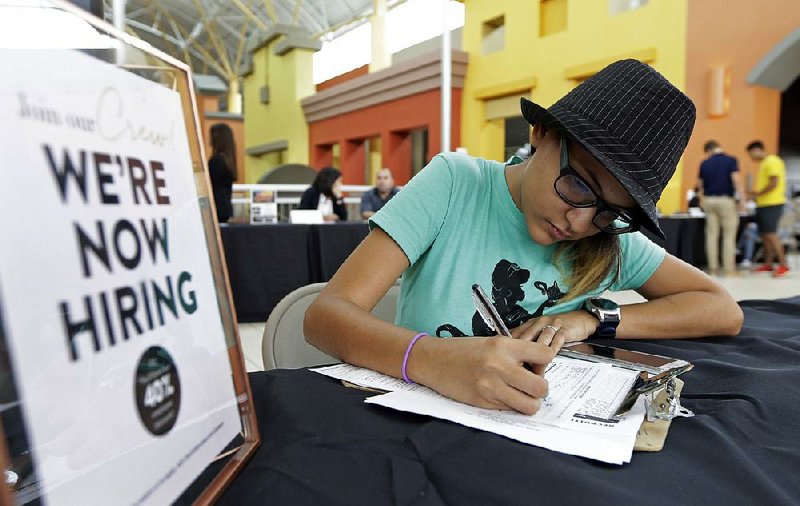 A job seeker fills out an application at a career fair in Sweetwater, Fla., in October. The U.S. jobless rate is 4.1 percent, and many economists believe wages should be rising faster than they are. 