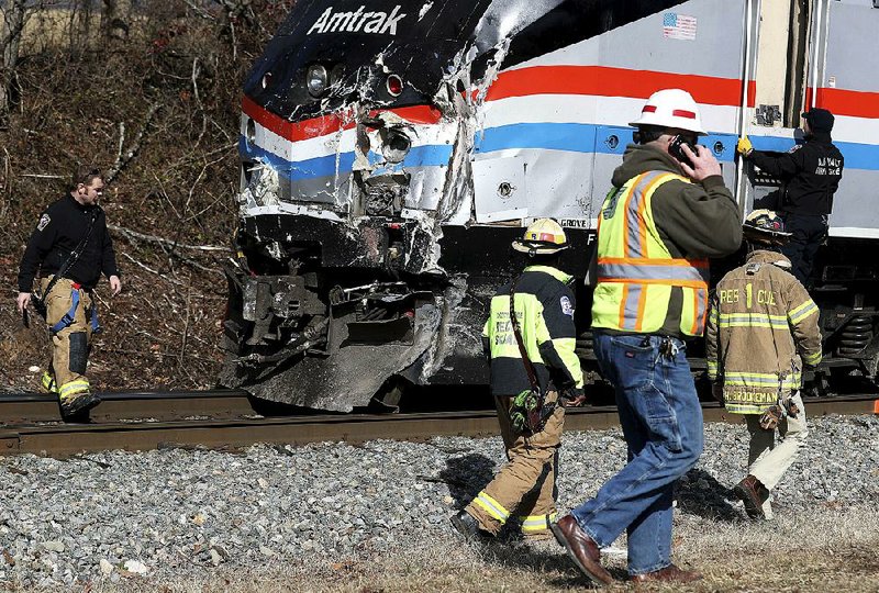 Responders walk past the damaged lead engine of an Amtrak train that crashed into a garbage truck in Crozet, Va. 