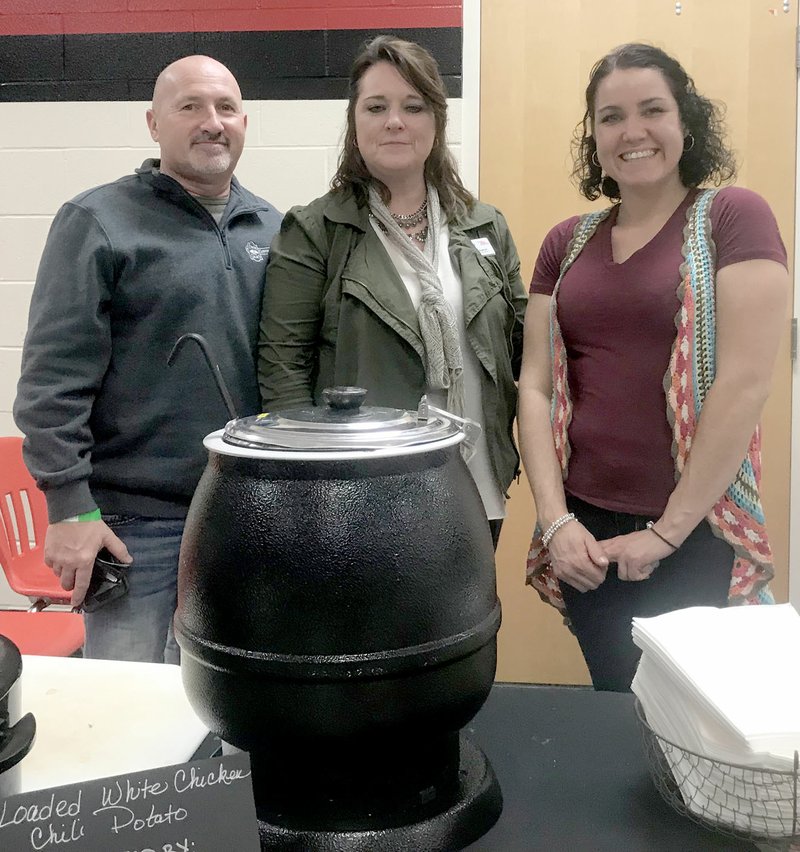 Photo by Sally Carroll Todd Daugherty (left) helped his wife, Janie Daugherty (center) and Summer Shafer as they served loaded white chicken chili potatoes at the International Food Fest Friday night. The group represented OPAA, which is the food service company for the McDonald County School District.