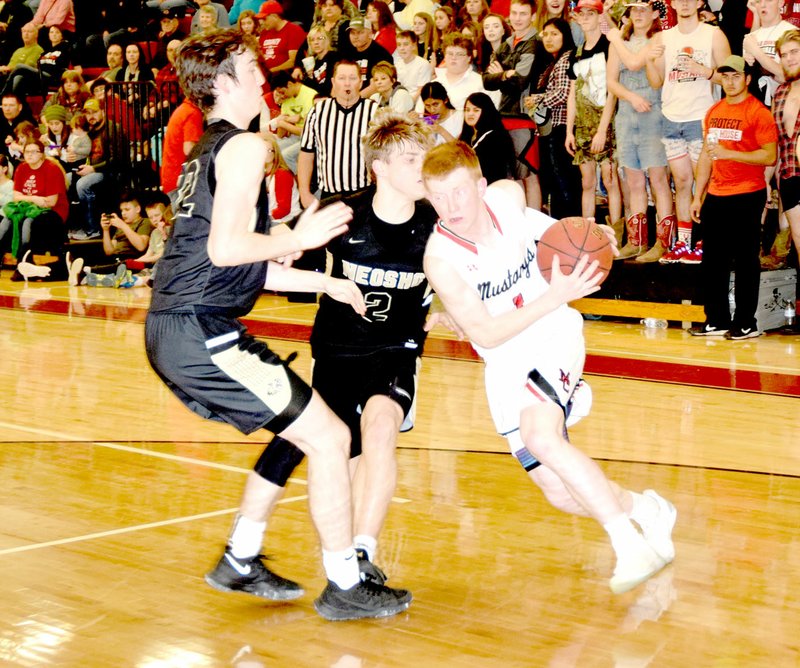 RICK PECK/SPECIAL TO MCDONALD COUNTY PRESS McDonald County's Blake Gravette drives around Neosho's Brady Wise (2) and A.C. Marion (22) during the Mustangs 50-44 win on Jan. 26 at MCHS.