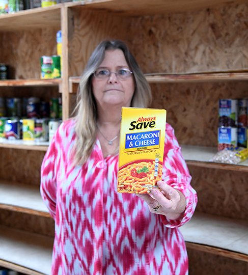The Sentinel-Record/Grace Brown EASILY MADE: Jeanie Saunders, social service director for The Salvation Army, holds a box of instant macaroni and cheese inside The Salvation Army's nearly empty food pantry Thursday. As of Thursday, The Salvation Army's pantry was reduced to cans of beans and vegetables, with no food items to make a complete meal. Saunders said foods that are easily prepared best fit the needs of those who receive packages of food from the pantry.