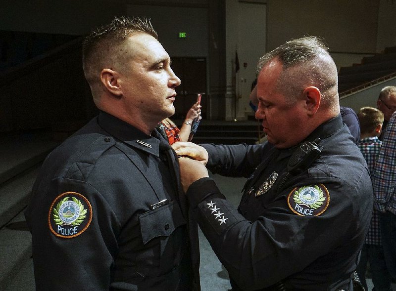 Little Rock police officer Larry Mears Sr. pins a badge on his son, Larry Jr., after a graduation ceremony Friday for 22 new officers. 