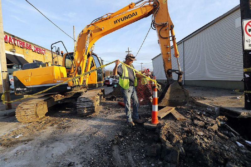 Workers fix a sewer main Wednesday below a New Orleans sidewalk. 