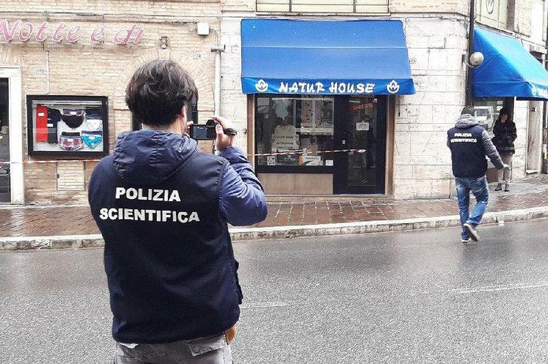 Italian forensic police take photos Saturday at the site of a shooting in Macerata. 